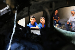 Palestinian children inspect the burned-out car after an attack by Jewish settlers on Palestinian homes. Jewish settlers set fire to cars, threw stones at homes, and wrote Hebrew slogans on houses in Jalud village, south of Nablus in the West Bank. They also damaged power lines between the villages of Jalud and Telfit, near Nablus in the West Bank.