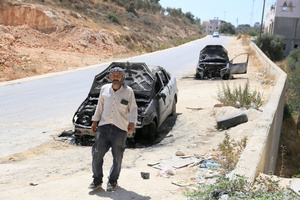 A Palestinian man walks past burned-out cars after an attack by Jewish settlers on Palestinian homes. Jewish settlers set fire to cars, threw stones at homes, and wrote Hebrew slogans on houses in Jalud village, south of Nablus in the West Bank. They also damaged power lines between the villages of Jalud and Telfit, near Nablus in the West Bank.
