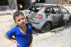 A Palestinian child stands next to a burned-out car after an attack by Jewish settlers on Palestinian homes. Jewish settlers set fire to cars, threw stones at homes, and wrote Hebrew slogans on houses in Jalud village, south of Nablus in the West Bank. They also damaged power lines between the villages of Jalud and Telfit, near Nablus in the West Bank.