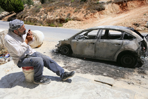A Palestinian man lights a cigarette next to a burned-out car after an attack by Jewish settlers on Palestinian homes. Jewish settlers set fire to cars, threw stones at homes, and wrote Hebrew slogans on houses in Jalud village, south of Nablus in the West Bank. They also damaged power lines between the villages of Jalud and Telfit, near Nablus in the West Bank.