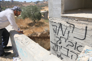 A Palestinian man looks at Hebrew graffiti on a wall of building under construction, painted by Jewish settlers in Jalud, south of Nablus in the West Bank. Jewish settlers set fire to cars, threw stones at homes, and wrote Hebrew slogans on houses in Jalud village, south of Nablus in the West Bank. They also damaged power lines between the villages of Jalud and Telfit, near Nablus in the West Bank.