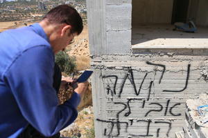 A Palestinian man takes photos of Hebrew graffiti on a wall of building under construction, painted by Jewish settlers in the village of Jalud, south of Nablus in the West Bank. Jewish settlers set fire to cars, threw stones at homes, and wrote Hebrew slogans on houses in Jalud village, south of Nablus in the West Bank. They also damaged power lines between the villages of Jalud and Telfit, near Nablus in the West Bank.