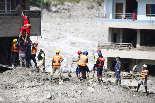 A woman climbs on top of her home to retrieve goods following flash floods at Devighat in Bidur Municipality. The floods, triggered by a glacial collapse, has killed at least 270 people and left 826 others out of contact, according to Nepalese authorities, with search and rescue operations continuing.