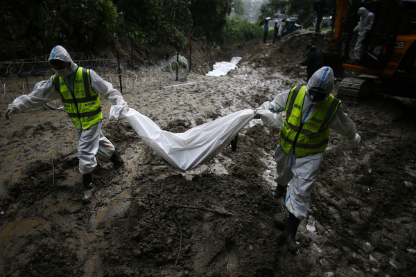 (EDITORS NOTE: Image depicts death) 
Security personnel carry a body of unidentified flood victim at a temporary burial site at Gokarna. Authorities have begun to temporarily bury unidentified remains, recovered from the devastating floods. DNA samples, photographs, and other identifying information are being collected before burial so families can later reclaim the remains of their people for final rites. The disaster killed more than 1,000 people in Nepal, with thousands still missing.