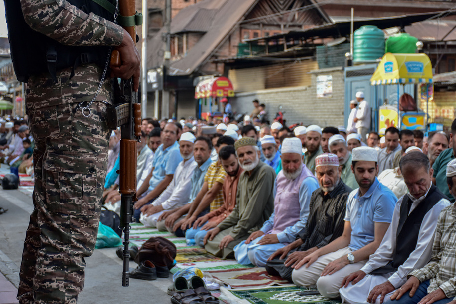 Kashmiri Muslims offer prayers as a paramilitary trooper stands alert outside the shrine of Naqshband Sahib during an annual festival locally known as 