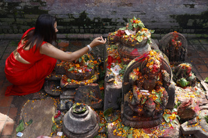 A woman prays during the Teej festival at Pashupatinath Temple. Married and unmarried Hindu women observe fasting during the festival. Married women traditionally abstain from food and water while praying for the longevity, peace, and prosperity of their husbands and families, while unmarried women fast in the hope of being blessed with good husbands.