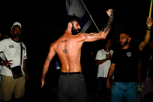 A protester who survived the Nova music festival seen showing his Nova tattoo on his back during a protest against the filmmakers of NAZA. Right-wing activists and their supporters protest outside the home of the parents of Rachel Szor, co-director of NAZA, which was awarded the Special Jury Prize at the 83rd Venice International Film Festival on September 12. The demonstration was led by right-wing activists Ziv Baraness and Mordechai David, who are involved in the election campaign of Itamar Ben Gvirí's Otzma Yehudit party. Protesters criticized the film's content, alleging that testimonies featured in it contain blatant falsehoods and claiming that the film contributes to antisemitism worldwide.