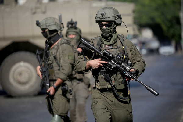 Israeli soldiers take positions near armored Israeli military vehicles blocking the main road at the entrance to the Al-Ain refugee camp, west of Nablus in the West Bank, during an Israeli military operation to search for combat materials. Residents reported that the army raided and searched homes and arrested five people, and some people were injured after being severely beaten.