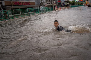 A child moves through floodwater on Phetchaburi Road. Floodwaters inundate major roads, including Phetchaburi Road and the Pridi Banomyong neighborhood in Bangkok, following a record monsoon downpour that prompted a capital-wide disaster declaration. Municipal pumps operate at full capacity to drain overflowing canals.