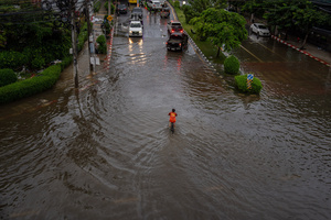 A kid rides his bicycle through floodwater as vehicles pass along Phetchaburi Road. Floodwaters inundate major roads, including Phetchaburi Road and the Pridi Banomyong neighborhood in Bangkok, following a record monsoon downpour that prompted a capital-wide disaster declaration. Municipal pumps operate at full capacity to drain overflowing canals.