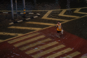 A pedestrian crosses a waterlogged street in the Pridi area of Bangkok. Floodwaters inundate major roads, including Phetchaburi Road and the Pridi Banomyong neighborhood in Bangkok, following a record monsoon downpour that prompted a capital-wide disaster declaration. Municipal pumps operate at full capacity to drain overflowing canals.