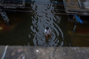 A person wades through floodwater in a residential lane in the Pridi area of Bangkok. Floodwaters inundate major roads, including Phetchaburi Road and the Pridi Banomyong neighborhood in Bangkok, following a record monsoon downpour that prompted a capital-wide disaster declaration. Municipal pumps operate at full capacity to drain overflowing canals.