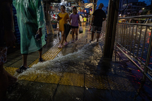 Pedestrians make their way along a flooded pavement in the Pridi area of Bangkok. Floodwaters inundate major roads, including Phetchaburi Road and the Pridi Banomyong neighborhood in Bangkok, following a record monsoon downpour that prompted a capital-wide disaster declaration. Municipal pumps operate at full capacity to drain overflowing canals.