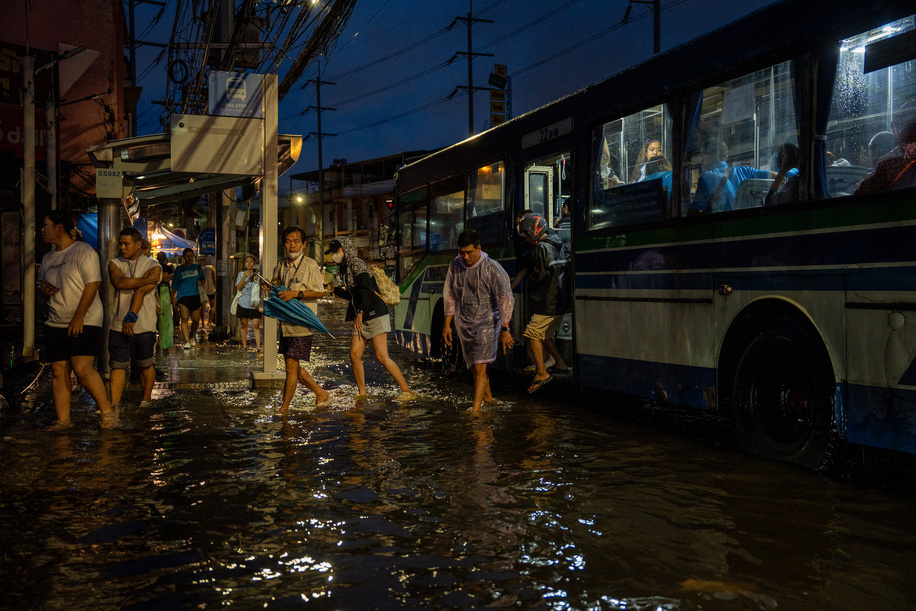 Passengers step through floodwater beside a bus in the Pridi area of Bangkok. Floodwaters inundate major roads, including Phetchaburi Road and the Pridi Banomyong neighborhood in Bangkok, following a record monsoon downpour that prompted a capital-wide disaster declaration. Municipal pumps operate at full capacity to drain overflowing canals.