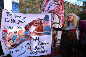 A protester seen standing with a hand painted banner depicting the Battle of Cable Street, outside the Tower Hamlets town hall during the rally. The 90th anniversary of the Battle of Cable Street is commemorated on Sunday 4 October 2026 in the east end of London. Despite the make-up having changed greatly over the last nine decades, thousands still marched through the streets to oppose Fascism and Zionism. In 1936, over 100,000 Jewish residents, Irish dockers, trade unionists, and local working-class communities stood shoulder to shoulder and repelled Sir Oswald Mosley's British Union of Fascists.