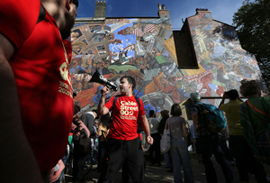 A supporter of the communist party seen chanting his message through a megaphone as they march past the Cable Street mural during the rally. The 90th anniversary of the Battle of Cable Street is commemorated on Sunday 4 October 2026 in the east end of London. Despite the make-up having changed greatly over the last nine decades, thousands still marched through the streets to oppose Fascism and Zionism. In 1936, over 100,000 Jewish residents, Irish dockers, trade unionists, and local working-class communities stood shoulder to shoulder and repelled Sir Oswald Mosley's British Union of Fascists.