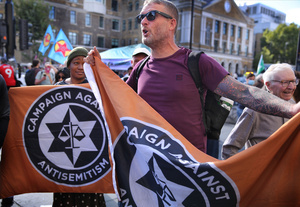 Protesters seen holding a flag of pro-Israel lobby group Campaign Against Antisemitism (CAA) outside the Tower Hamlets town hall during the rally. The 90th anniversary of the Battle of Cable Street is commemorated on Sunday 4 October 2026 in the east end of London. Despite the make-up having changed greatly over the last nine decades, thousands still marched through the streets to oppose Fascism and Zionism. In 1936, over 100,000 Jewish residents, Irish dockers, trade unionists, and local working-class communities stood shoulder to shoulder and repelled Sir Oswald Mosley's British Union of Fascists.