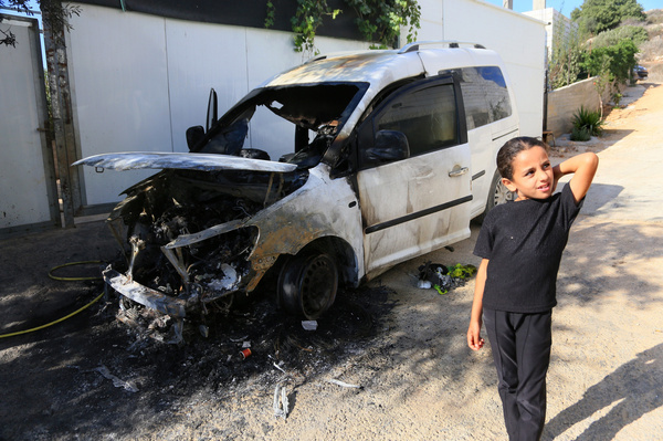 A Palestinian girl stands beside a vehicle which was burnt by rioting Jewish settlers, who also scrawled Hebrew slogans on the walls of homes in the village of Aqraba Groups of rioting settlers launched attacks on Palestinian villages, they set fire on home in the village of Burqa near Ramallah, pelting Palestinian vehicles with stones, and harassing Palestinian farmers who were harvesting olive.