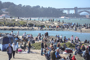 People watch the air show along the waterfront. Crowds gather along the waterfront to watch the San Francisco Fleet Week Air Show as aircraft, including the U.S. Navy Blue Angels, performed in the skies over the city. The annual event is part of San Francisco Fleet Week, which celebrates the U.S. military and honors the men and women serving in the armed forces.