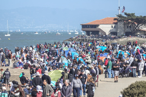 People watch the air show along the waterfront. Crowds gather along the waterfront to watch the San Francisco Fleet Week Air Show as aircraft, including the U.S. Navy Blue Angels, performed in the skies over the city. The annual event is part of San Francisco Fleet Week, which celebrates the U.S. military and honors the men and women serving in the armed forces.
