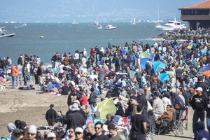 People watch the air show along the waterfront. Crowds gather along the waterfront to watch the San Francisco Fleet Week Air Show as aircraft, including the U.S. Navy Blue Angels, performed in the skies over the city. The annual event is part of San Francisco Fleet Week, which celebrates the U.S. military and honors the men and women serving in the armed forces.