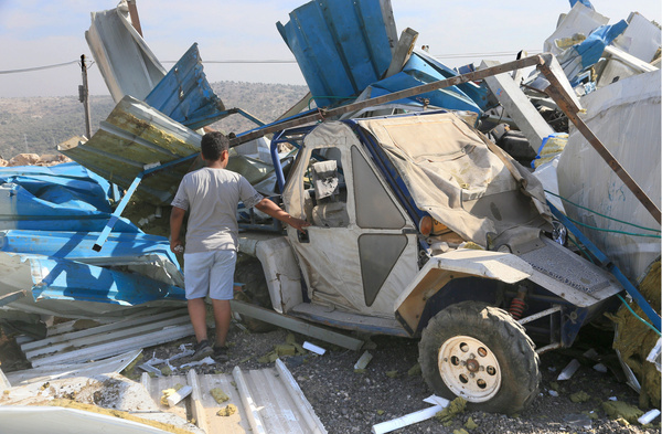 A Palestinian child inspects his parents' vehicle amidst the destruction left by Israeli military bulldozers in the village of Haris, southwest of Nablus. Israeli army forces demolished five workshops and homes, citing security reasons; the structures were located near roads adjacent to Israeli settlements in the occupied West Bank.