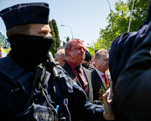 The Ambassador of Russian Federation Sergey Andreev, surrounded by a Polish police guard, moves towards his car covered with fake blood. On the 77th anniversary of the Red Army victory over Nazi Germany Ukrainian activists performed at the Soviet soldiers cemetery in Warsaw as they protested against Russian invasion of Ukraine. Activists banned the Russian delegation headed by Sergey Andreev, the Ambassador of the Russian Federation in Poland, from entering the Cemetery. During that attempt diplomats were doused with fake blood by the Ukrainian activists.