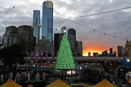 A giant Christmas tree is illuminated at Federation Square, drawing crowds of visitors. Melbourne's night skies glow with festive Christmas lights and decorations with stunning displays and a vibrant atmosphere.
