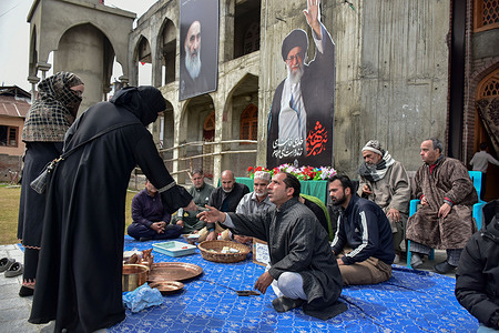A volunteer of Shiite Muslim community collects Indian Rupee banknotes from a woman during a donation drive in support of war-stricken Iran, in Srinagar. As the West Asia conflict entered its fourth week, residents of Kashmir have come forward with donations of cash, gold jewelry, and copper utensils to support people affected by the war in Iran.
