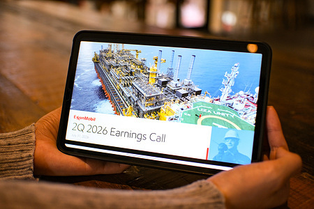In this photo illustration, a woman is browsing ExxonMobil's 2Q 2026 earnings call presentation on a tablet.