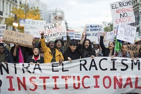 A huge crowd of protesters seen holding placards protesting behind a huge banner during a demonstration against racism in Madrid. Demonstrators demanded that white people repair the damage that racism has done to black people.