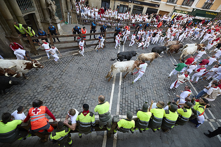 Several runners race infront of the bulls through the streets of Pamplona during the Running of the Bulls at the San Fermín 2025 festivities. The bulls are from the Victoriano del Río ranch.