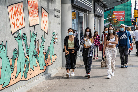 Women wearing face masks as a precaution walking in downtown Toronto during COVID-19 pandemic.