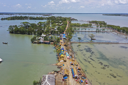 (EDITORS NOTE: image taken with a drone) In coastal area's people take temporary shelter on the embankment after the landfall of cyclone Amphan last month at Koyra in Khulna.
Thousands of shrimp enclosures have been washed away, while numerous thatched house, trees, electricity and telephone poles, dykes and croplands were damaged and many villages were submerged by the tidal surge of the Amphan in Khulna District.