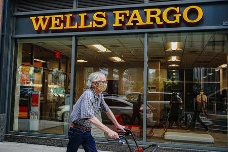 An elderly man wearing a face mask passes by a Wells Fargo branch in Midtown area of New York City.