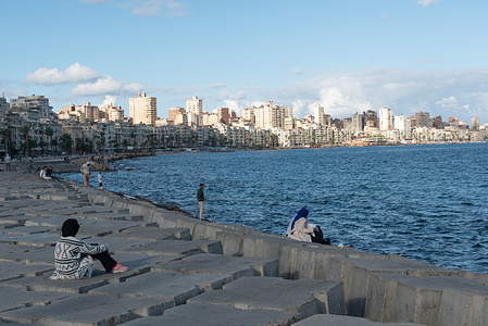 People sit on concrete blocks positioned as a defence against rising Mediterranean sea levels along the Corniche of Alexandria, the seconds largest city in Egypt.