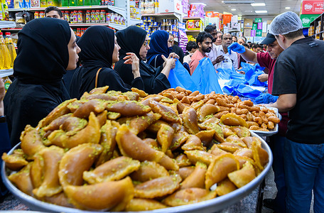 Customers buy traditional sweets at a shop on the first day of the Islamic holy month of Ramadan in Doha. Popular desserts including luqaimat and syrup-soaked pastries are prepared in large quantities to meet increased demand during the fasting month.