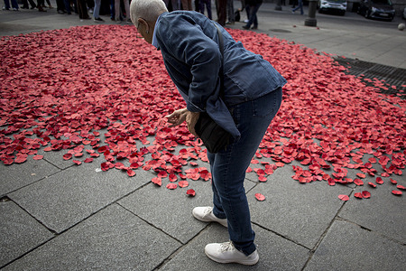 A person picks up one of the thousands of paper poppies lying on the ground during an event in front of the Spanish Ministry of Foreign Affairs. Each poppy represents one of the Palestinians killed in the past two years at the hands of the Israeli army. The event was organized by the Spanish Commission for Refugee Aid (CEAR).