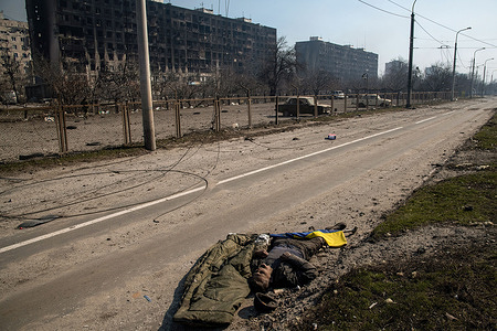 (EDITORS NOTE: Image depicts death)
A deceased man lies next to a Ukrainian flag in a road reduced to ruins by intense artillery bombardment in the port city of Mariupol. The battle between Russian / Pro Russian forces and the defencing Ukrainian forces lead by Azov battalion continues in the port city of Mariupol.