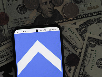 In this photo illustration, an Uptake Technologies logo seen displayed on a smartphone with United States Dollar notes and coins in the background.