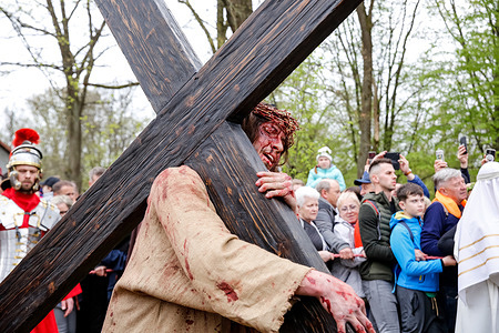 Actor playing Jesus from Nazareth walks with a cross during the procession in the Way of the Cross during the Mystery of Christ's Passion on Good Friday organized at Kalwaria Zebrzydowska sanctuary the biggest way of the Cross event.