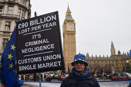 An activist holds a placard stating that the UK has lost 90 billion pounds per year as a result of leaving the Customs Union and single market, during the weekly pro-EU and anti-Brexit protest in Parliament Square. The government has announced that the UK will rejoin the European Union's Erasmus student exchange programme as the UK seeks closer ties with the EU.