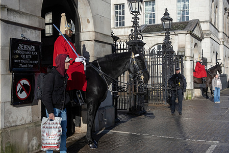 People take photos by the horse guards in the Whitehall in London. The Household Cavalry Regiment, the soldiers who stand guard on horseback in Whitehall, London are made up of two main groups: the Life Guards and the Blues and Royals. This tradition dates back to the restoration of King Charles II in 1660. The mounted guards stationed daily from 10 am to 4 pm.