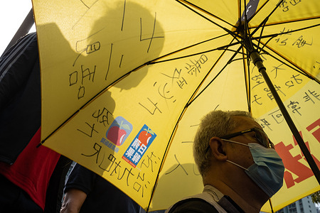 A supporter of pro-democracy activists holds an umbrella as he lines up outside the West Kowloon Court. 47 Hong Kong pro-democracy activists charged with conspiracy to subvert state power under the National Security Law attend their first court hearing as thousands of supporters gather outside the court to express solidarity.