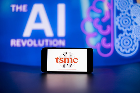 In this photo illustration, the Taiwan Semiconductor Manufacturing Co. Ltd (TSMC) logo seen displayed on a mobile phone screen with the AI (artificial intelligence) revolution symbol in the background.