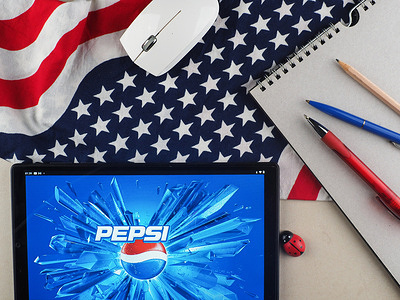 In this photo illustration, Pepsi logo seen displayed on a tablet with a background of the American flag.