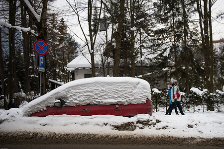 A couple passes by a car covered in snow in Zakopane.
