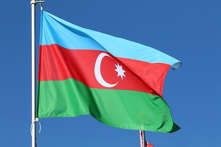 The national flag of the The Republic of Azerbaijan, fluttering in the wind on a flagpole in Saint Petersburg.