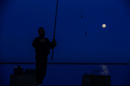 A silhouetted man fishes under the glow of the strawberry full moon at Williamstown Beach. The Full Strawberry moon illuminated the night sky over Williamstown Beach in Melbourne, attracting many to observe the rare event. The June full moon, traditionally called the strawberry moon, signals the time of strawberry harvesting. This year’s moon appeared approximately 14% larger and 30% brighter than usual due to its closer proximity to Earth.