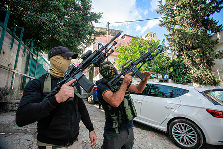 Armed Palestinians stand on guard at the entrance to the Balata refugee camp, east of the city of Nablus, in the northern West Bank.